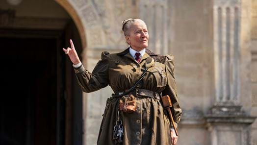 Image of actor Emma Thompson as Miss Trunchbull standing in the school's entrance